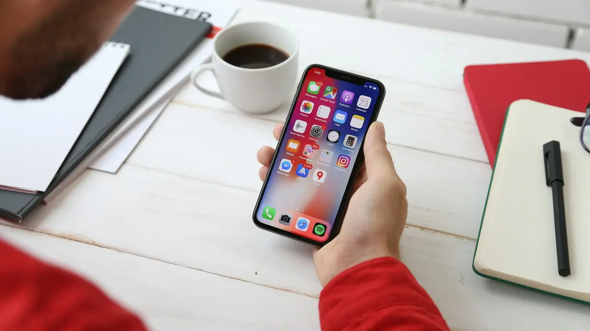 Tay cầm điện thoại thông minh trên bàn làm việc, minh họa tải app 789Club